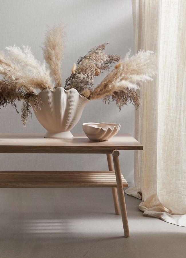 shell shaped vase on bench with pampas grass