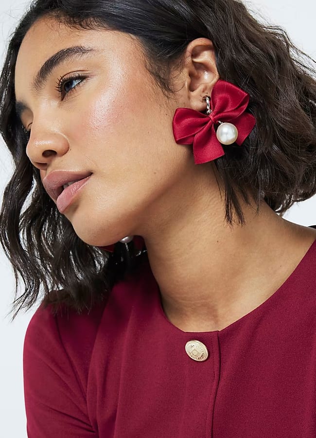 model wearing RIVER ISLAND Red Christmas Ribbon Bow Pearl Drop Earrings