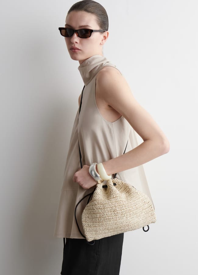 model holding MINI CAVATELLI CLUTCH BAG - STRAW