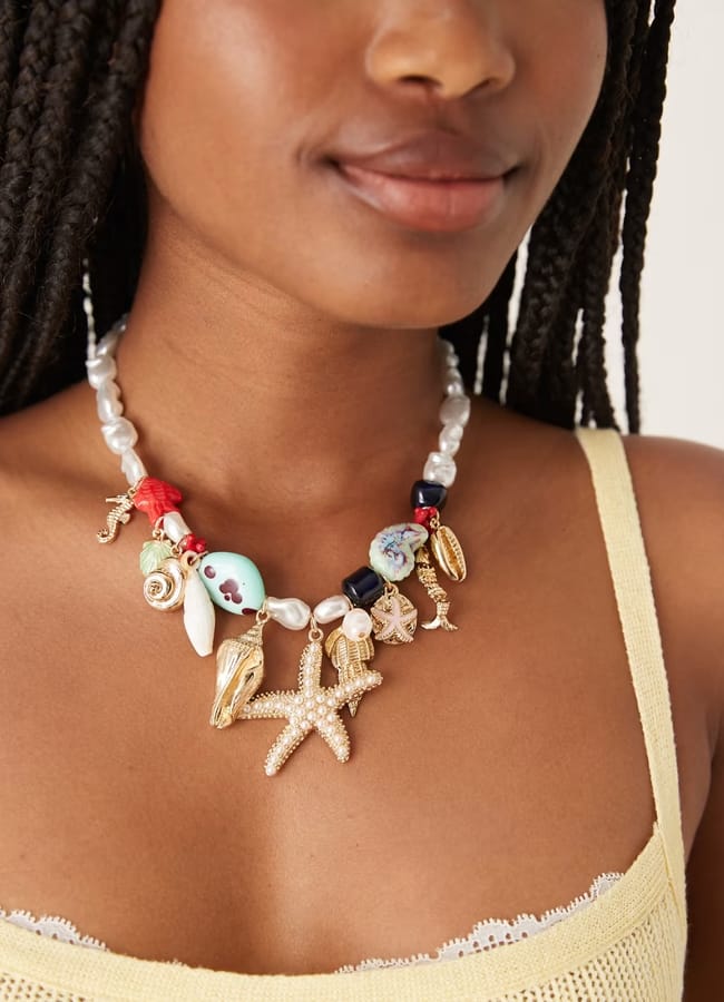 model close up of neck and chest wearing ASOS DESIGN Limited Edition faux pearl necklace with large sea-life charms