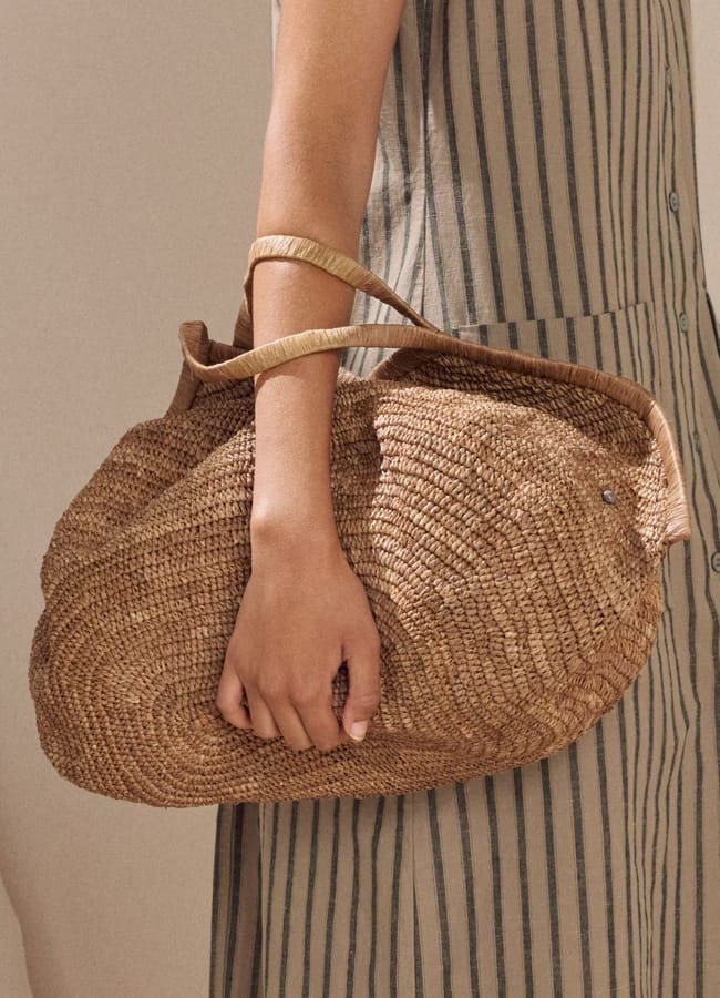 close up of model's hand holding Poetry Large shell-shaped bag