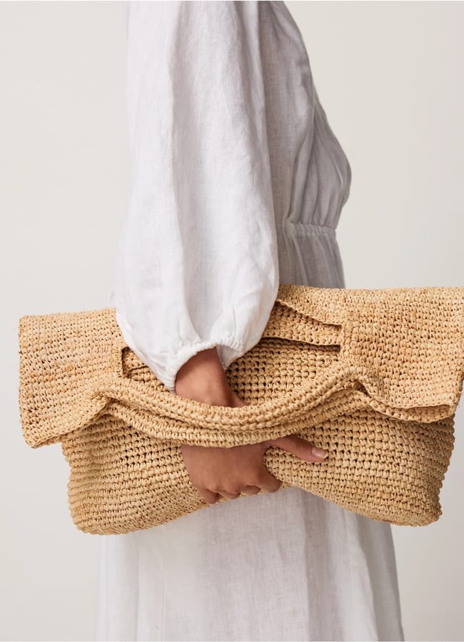model holding TWC Raffia Foldover Large Bag