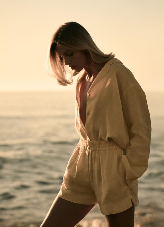model on beach wearing linen shirt and shorts in lemon yellow