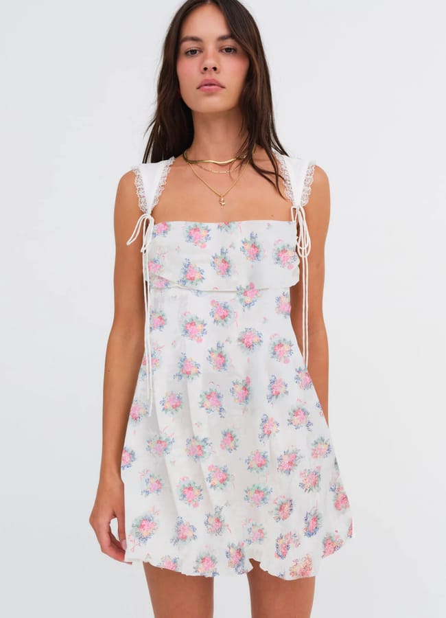 model wearing white mini dress with pink floral print
