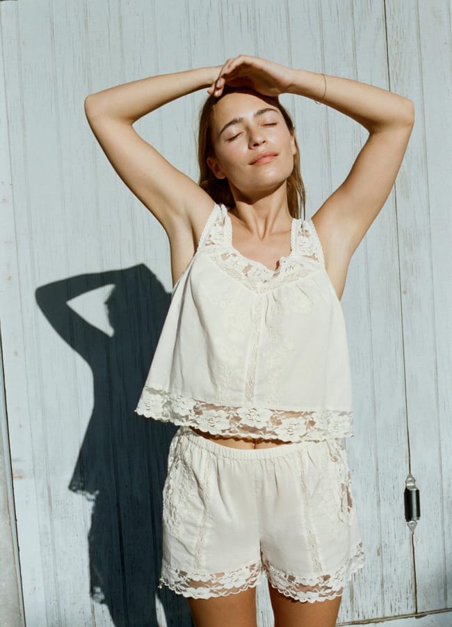 model wearing strappy embroidered top and vest with arms up