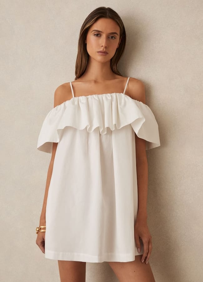 model wears Lucia Cotton Off Shoulder Mini Dress in Ivory Cream