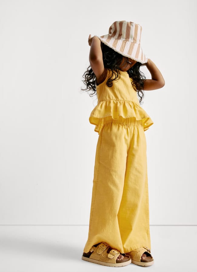 little girl wearing yellow co-ord and sunhat