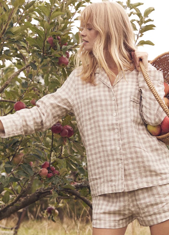 model in Piglet in Bed Mushroom Gingham Pyjama Shorts Set picking apples from tree