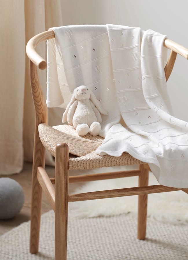 Organic Cotton White Pointelle Heart Baby Blanket on chair