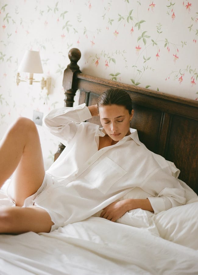 model in bed wearing white cotton pjs