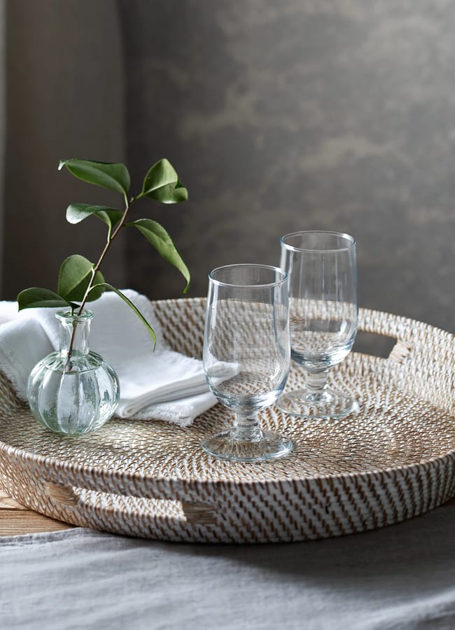 whitewashed rattan round tray with glasses on