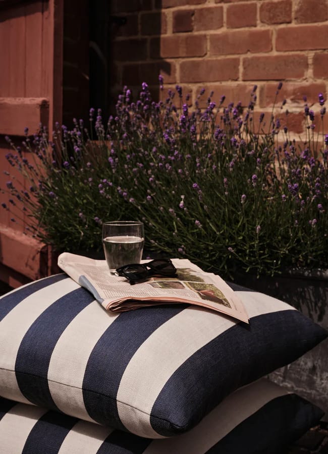 striped outdoor cushions with newspapers and glass on