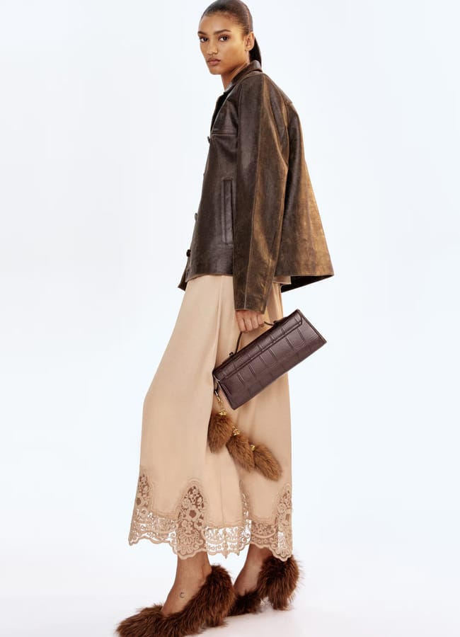 model wearing leather brown jacket and blush lace skirt
