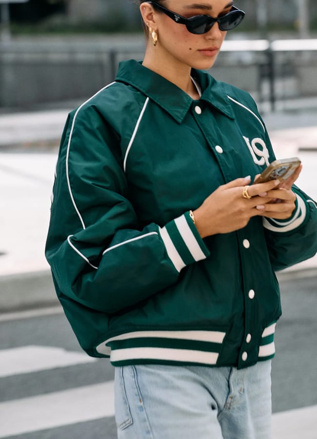 model walking in street wearing green bomber jacket
