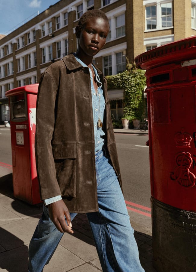 model walking down street wearing suede jacket and jeans