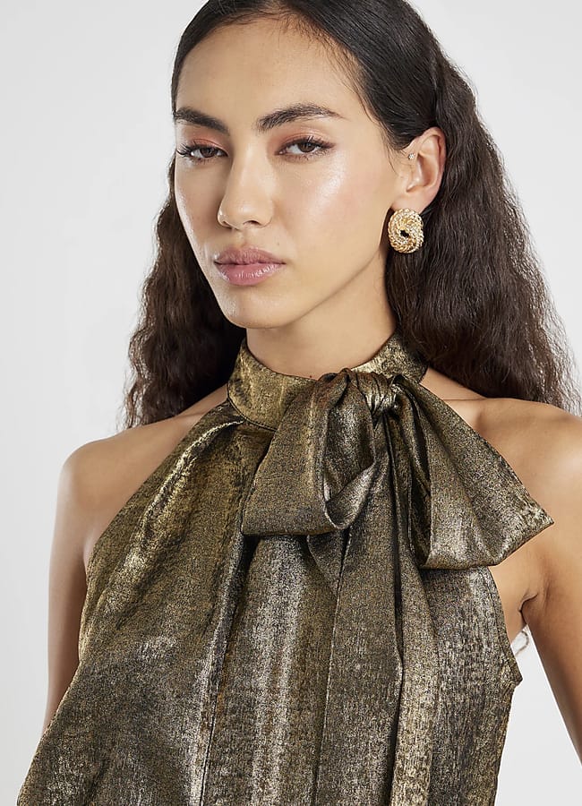 model wearing gold halterneck top