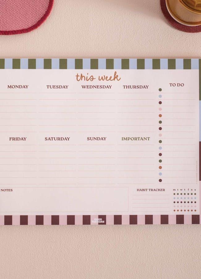 A colourful weekly planner pad on a desk, featuring sections for each day, to-do list, important notes, habit tracker, and notes. With striped borders, it adds flair—perfect for organising plans before transferring them into your 2026 diaries.