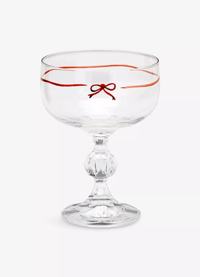 A clear glass coupe with a decorative red ribbon and bow design near the rim, and a faceted stem—perfect for adding festive charm to your Christmas tablescape.