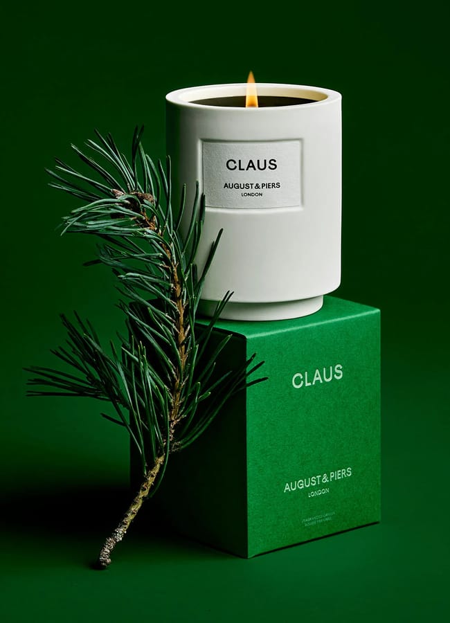 A white winter candle labelled CLAUS AUGUSTA PIERS sits on a green box of the same name.