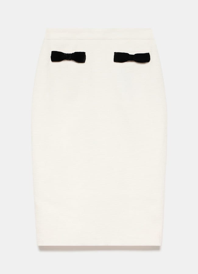 A white pencil skirt featuring bow fashion with two small black bow accents near the waistband on the front.