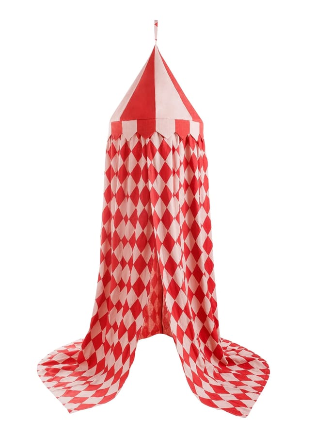 Red and white fabric play tent shaped like a circus tent, featuring a pointed top and hanging drapes with a diamond pattern—a whimsical nod to the Unexpected Red Theory in interior design, displayed against a white background.