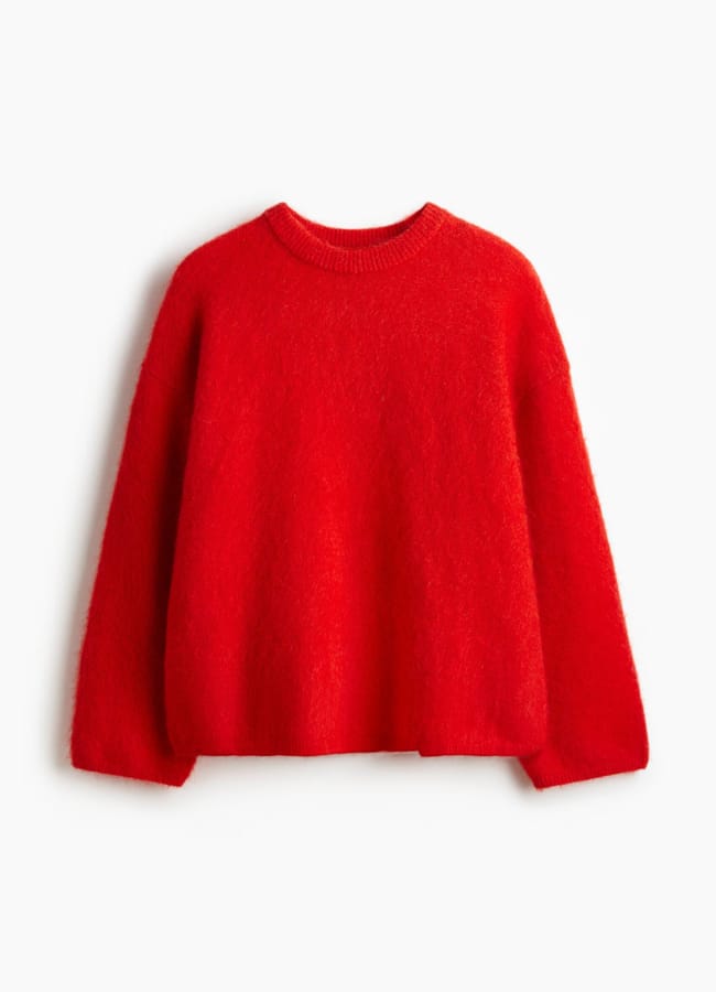 A bright red, long-sleeve, crew neck jumper with a loose, relaxed fit—perfect for pairing with brown trousers—is displayed on a plain white background.