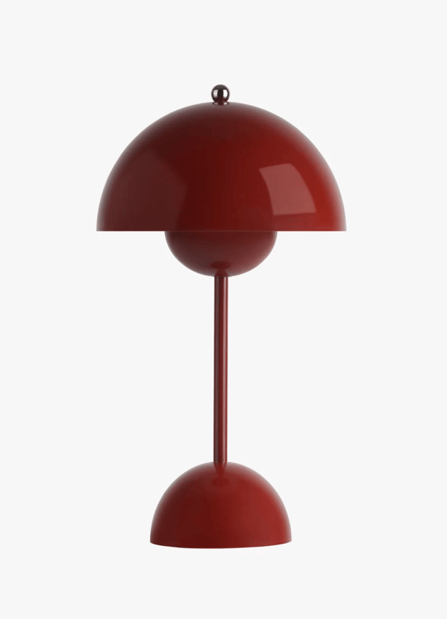 A modern red table lamp with a dome-shaped shade and base, connected by a thin vertical stem, perfectly captures Unexpected Red Theory—a bold interior design trend set to shape 2026—against a plain white background.