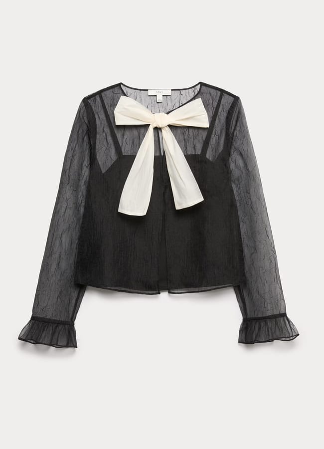 A sheer black long-sleeve blouse with ruffled cuffs, a square neckline, and a large white bow at the collar—this piece highlights bow fashion with its delicate, lightweight texture and slightly loose fit.