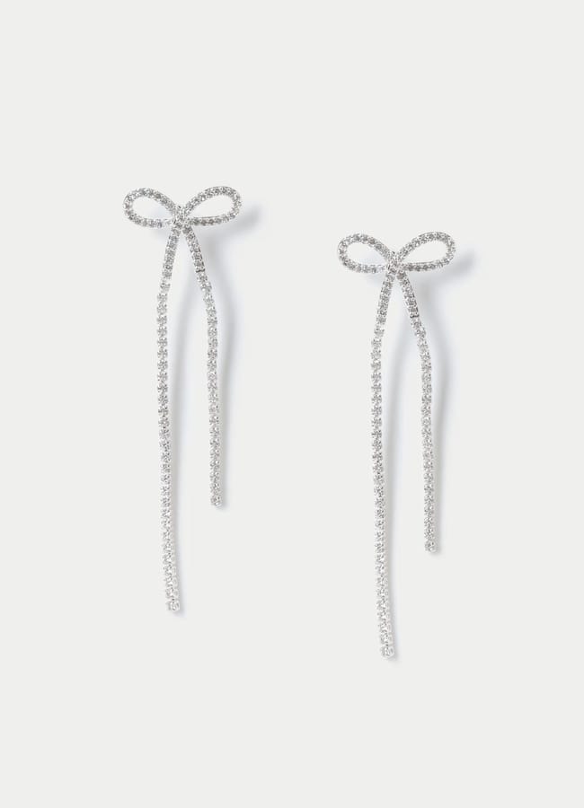 A pair of sparkling earrings shaped like delicate bows, each with two long, dangling tails, perfect for adding a touch of bow fashion to any outfit, set against a plain white background.