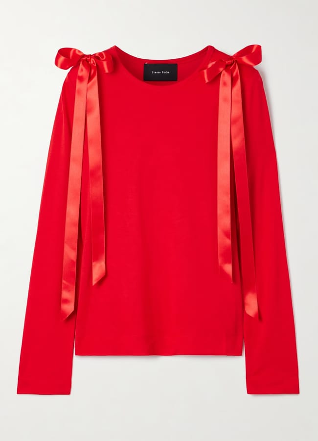 A bright red long-sleeve top with two shiny red satin ribbon bows tied at each shoulder, perfect for bow fashion lovers. The shirt features a simple, straight cut and a round neckline.