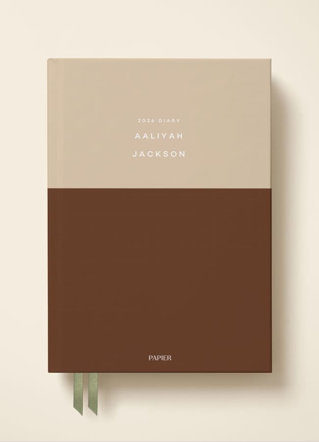 A 2024 diary with a minimalist design, featuring a beige top half and a brown bottom half, personalised with the name Aaliyah Jackson. Two green ribbon bookmarks hang from the bottom—a style also available in our 2026 diaries.