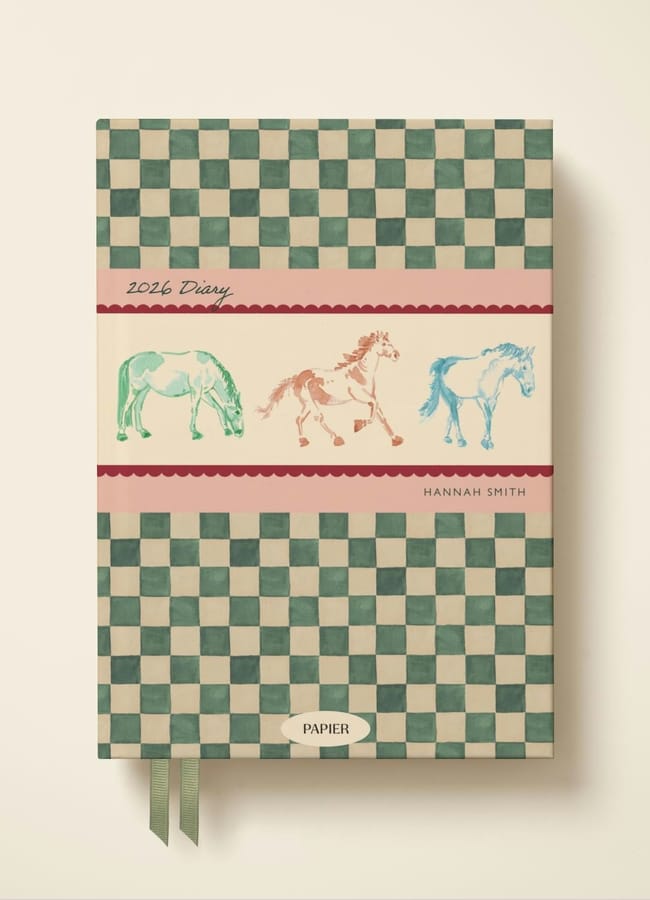 A 2026 diary with a green and cream chequerboard cover, featuring three illustrated horses in different colours on a central beige band, and the name Hannah Smith printed on the front—perfect for fans of unique 2026 diaries.