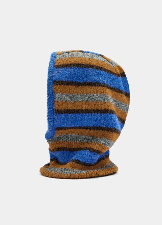 A knitted balaclava with horizontal stripes in blue, brown, and grey tones evokes chic fashion, displayed upright on a plain white background.