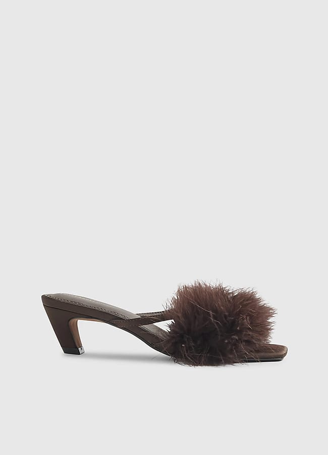 A brown open-toe heeled sandal with a fluffy, feather-like pom-pom detail on the upper strap, reminiscent of a festive Christmas tablescape, set against a plain light grey background.