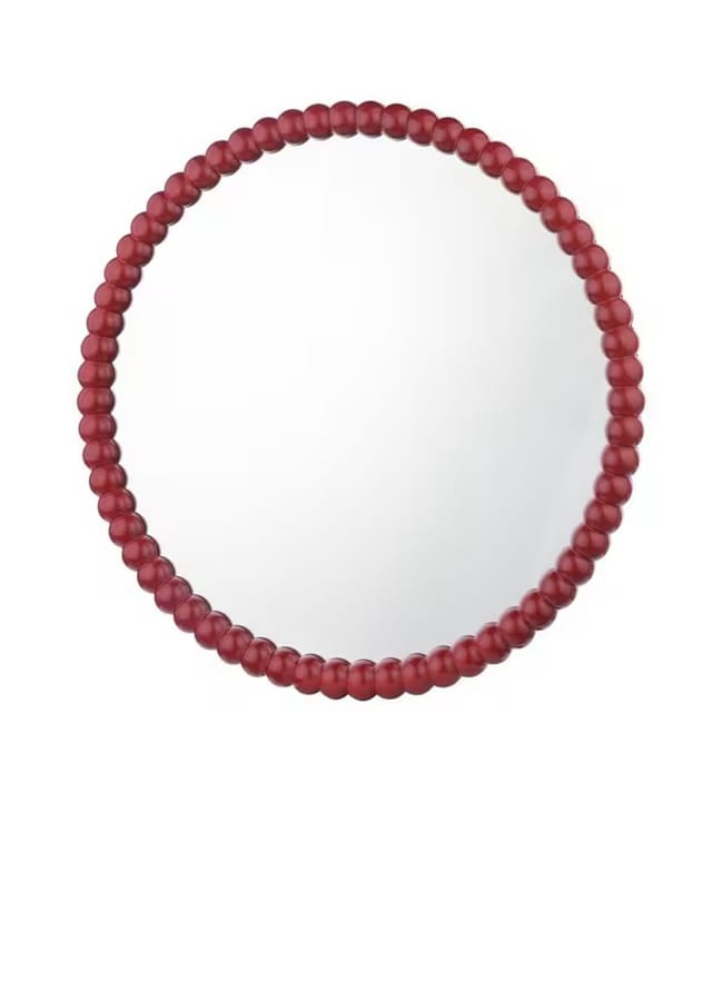 A round mirror with a frame made of evenly spaced, matt red beads illustrates the Unexpected Red Theory in Interior Design, set against a plain white background.