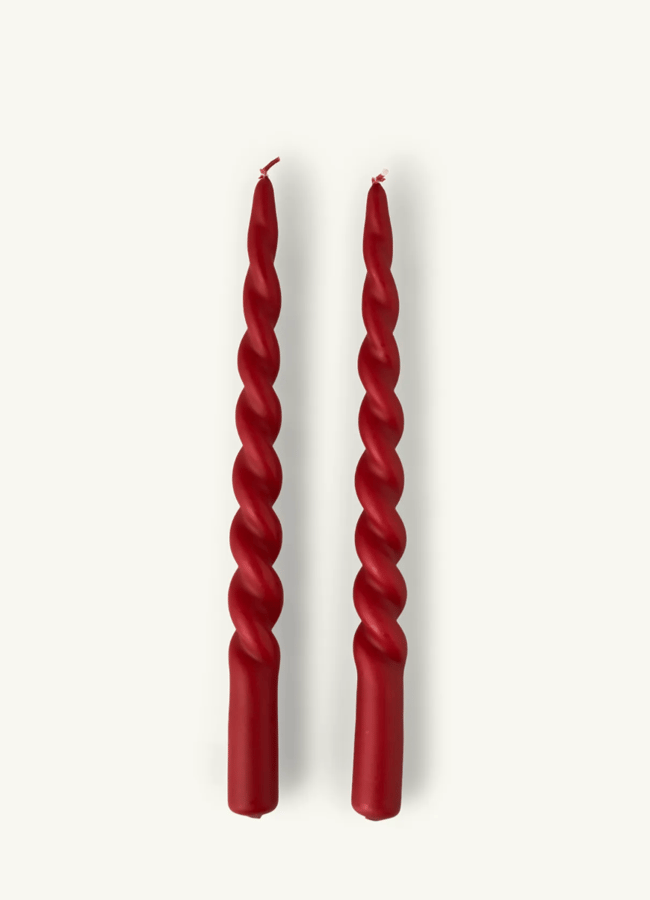 Two red, spiral-twisted taper candles are standing upright on a plain white background, perfect for enhancing a festive Christmas tablescape.
