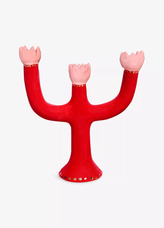 A red, three-armed ceramic candle holder shaped like a cactus channels the Unexpected Red Theory—perfect for bold 2026 interior design—with pink, flower-like holders and small gold dots along the base and top edges.
