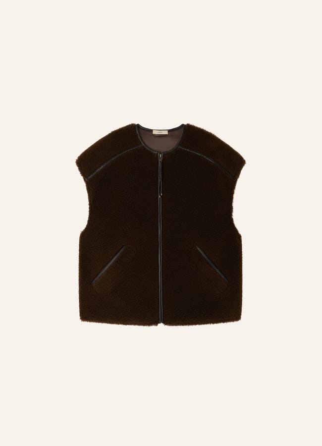 A sleeveless, dark brown shearling gilet with a front zip and two slanted pockets, perfect for pairing with brown trousers in chic fashion, displayed on a plain light background.