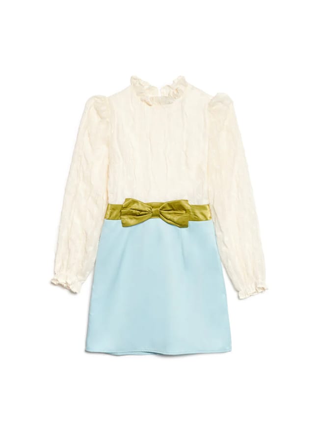 A long-sleeved dress with a cream textured top, high ruffled collar, and light blue skirt. The waist features a green velvet bow—a perfect example of elegant bow fashion.