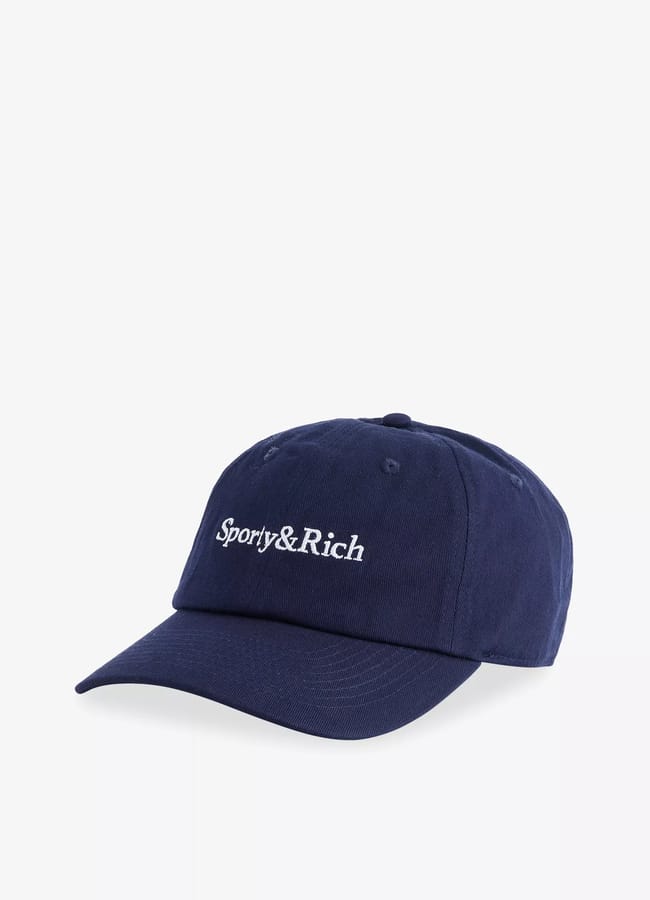 A navy blue baseball cap with the words Sporty & Rich embroidered in white on the front, displayed on a plain white background—a perfect accessory to complement the latest activewear styles.