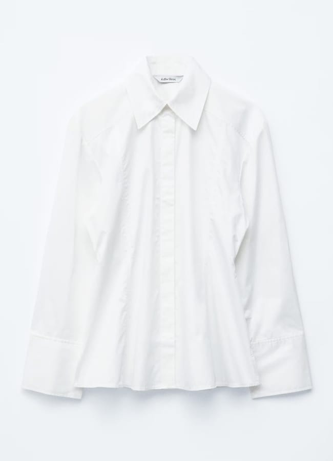A long-sleeved, white button-up shirt with a pointed collar, displayed on a flat white background—perfect for pairing with outfits with tights for a polished look.