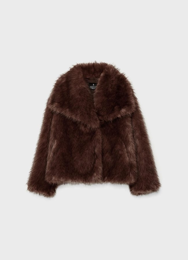 A brown faux fur jacket with long sleeves, a wide collar, and a slightly cropped cut displayed on a plain light grey background—a perfect piece for elevating your fashion game or pairing with brown trousers for a chicer look.