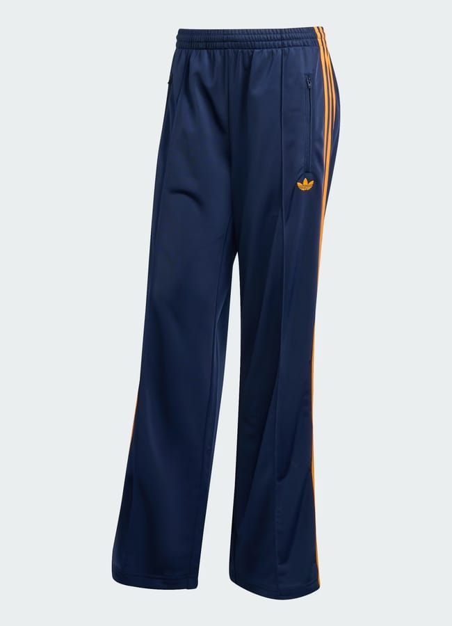 Navy blue Adidas track bottoms with gold stripes down the sides, a gold Adidas logo on the left thigh, zipped side pockets, and an elasticated waistband combine comfort and style in classic track bottoms fashion.