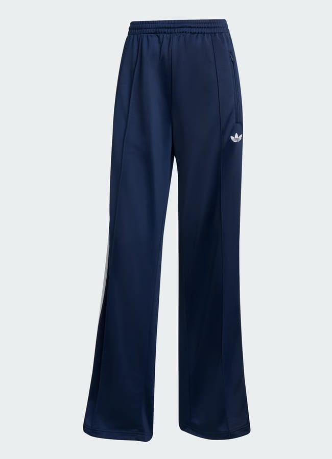 Navy blue Adidas track trousers featuring an elasticated waistband, wide legs, convenient side pockets, and a white Adidas trefoil logo on the left thigh—perfect for athletic or casual wear.