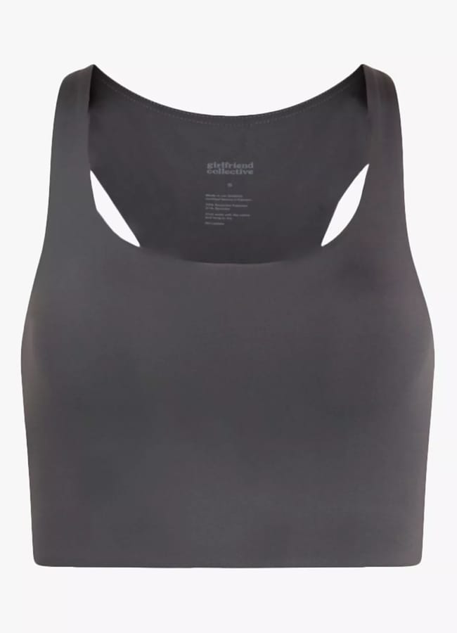 A dark grey racerback sports bra with a high neckline, featuring a smooth, seamless design perfect for athleisure looks and minimal branding on the inside back.