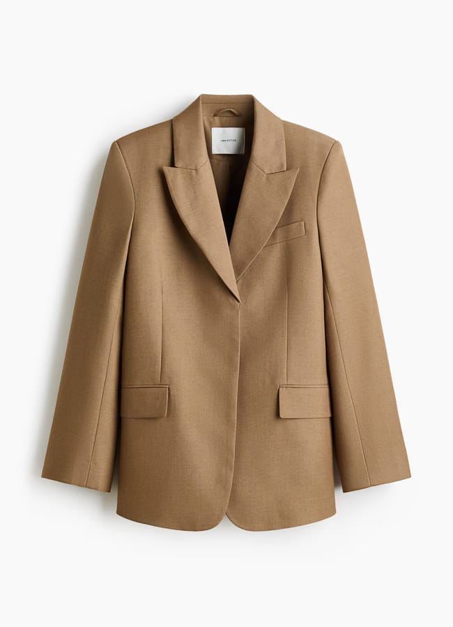 A single-breasted, camel-coloured blazer with notched lapels, two front flap pockets, and a tailored fit—this High Street Blazer is curated for the discerning Fashion Editor and displayed against a white background.