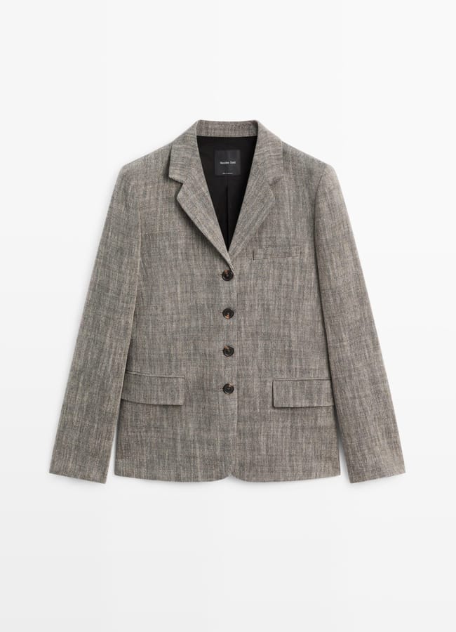 A grey, textured blazer with a notched lapel, three-button front, and multiple pockets—a perfect pick for Fashion Editors seeking standout High Street Blazers, displayed elegantly against a plain white background.