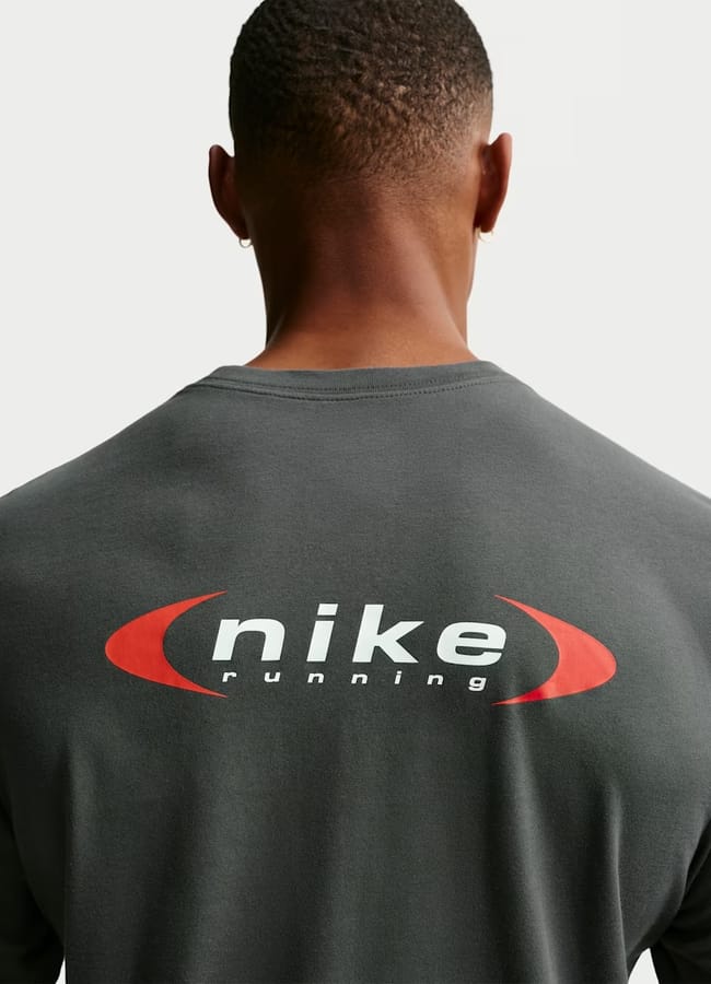 A person seen from behind wearing gym clothes for men—a dark grey shirt with the words nike running in white, surrounded by two red curved lines on the back.