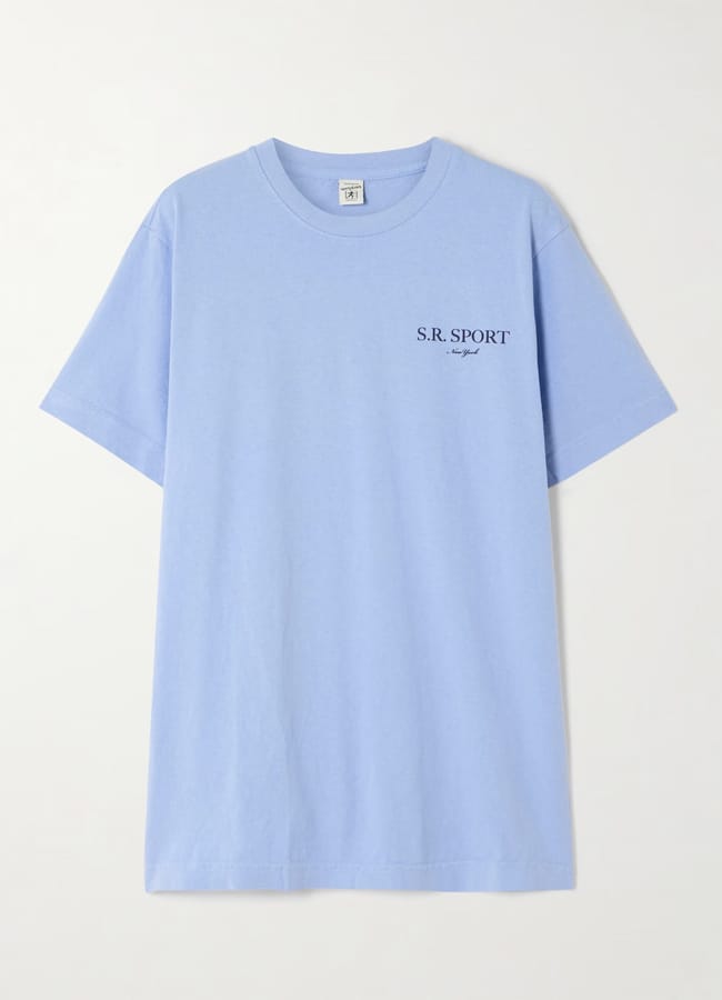 A light blue athleisure short-sleeve T-shirt with S.R. SPORT and cursive text printed in black on the left chest. The shirt is laid flat on a plain white background.