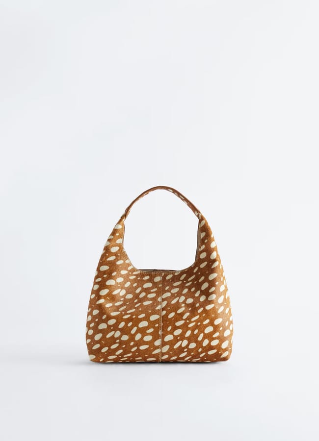 Brown handbag with short handle, featuring a white spotted pattern resembling deer fur, displayed against a plain light background—perfect for pairing with your favourite track bottoms.